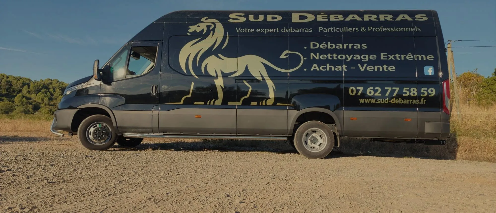 Le camion Sud Débarras vu de profil, portant la liste des prestations : débarras, nettoyage extrême, achat et vente