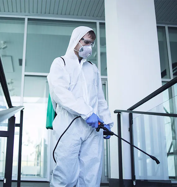 Technicien en combinaison de protection réalisant une désinfection sanitaire